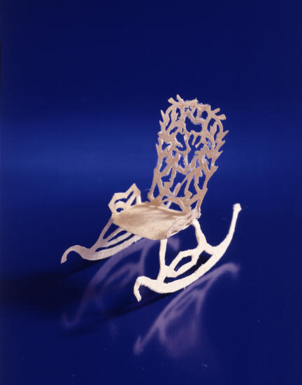 Кресло-качалка, вырезанная и сложенная так, что может качаться на ножках. Тонкий узор на спинке кресла